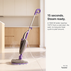 Purple and grey corded steam mop standing upright on light tile floor, emitting visible steam, with kitchen cabinets behind.