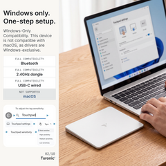 White glass touchpad on a wood desk beside a laptop showing Windows Trackpad settings on screen.